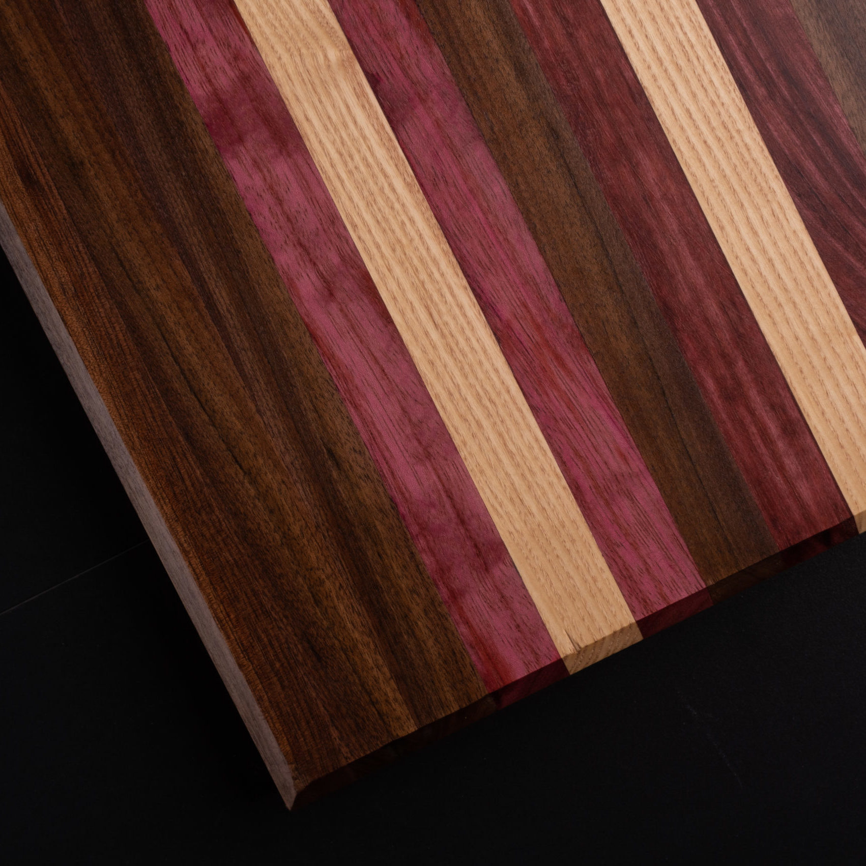 Multi-colored grained wooden cutting board. Ash, walnut, paduak.