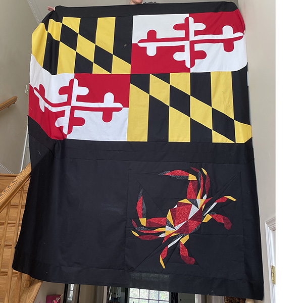 large quilt - black, yellow, red, and white. The Maryland flag is across the top, and a crab is on the bottom.