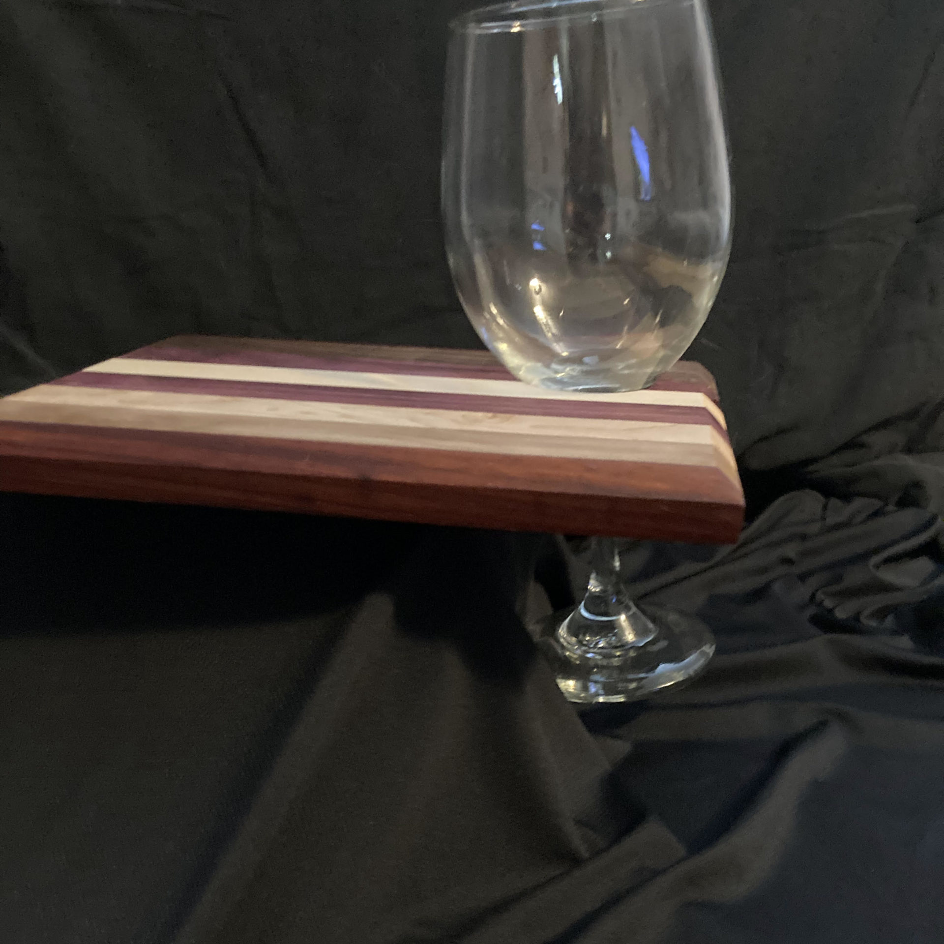 Wine glass carrier - multi colored wooden board with hole, holding a crystal wine glass